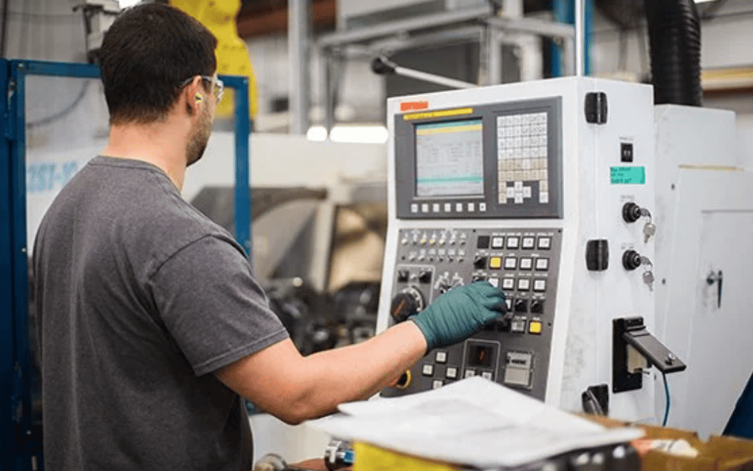 An employee wearing safety gear working on equipment in a factory